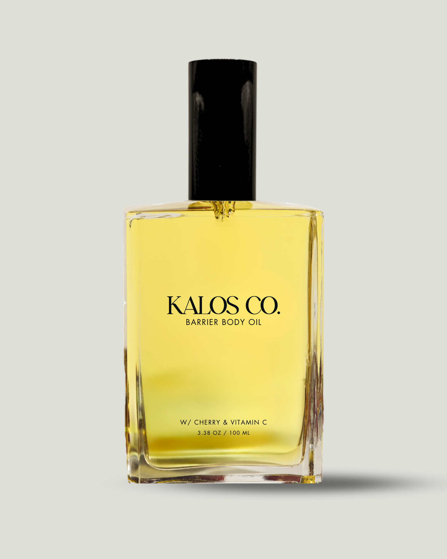 Yellow bottle of Kalos Co. Barrier Body Oil with black cap on a light gray background