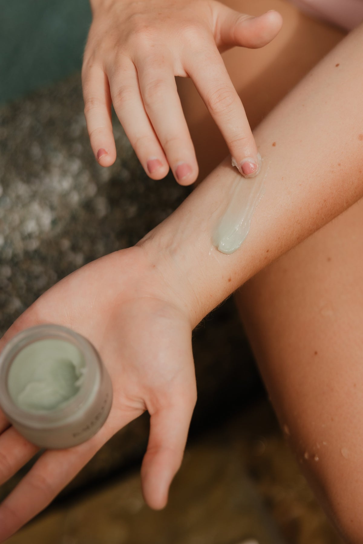 woman applying dewy face balm to arm