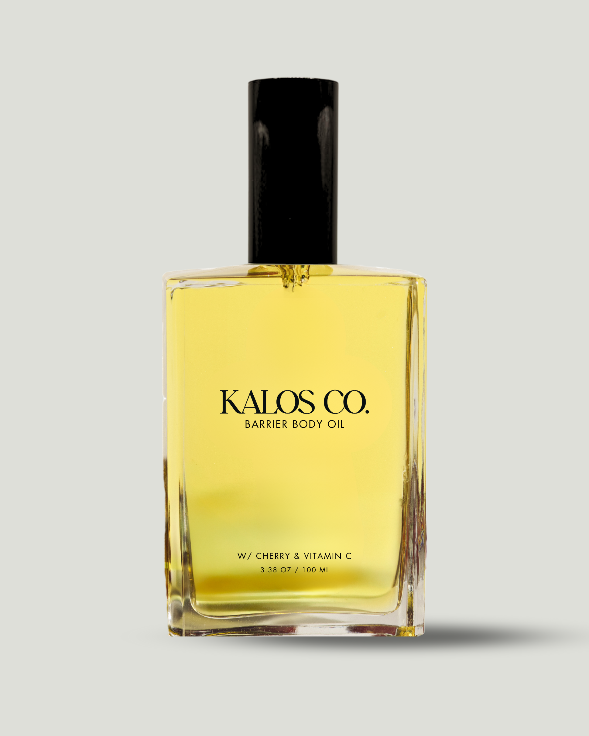 Yellow bottle of Kalos Co. Barrier Body Oil with black cap on a light gray background